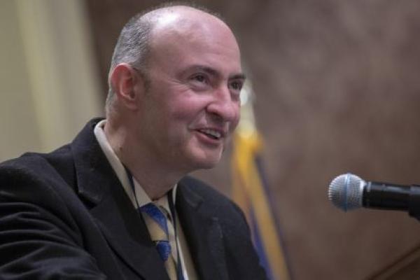 A man dressed in a suit speaks at a podium