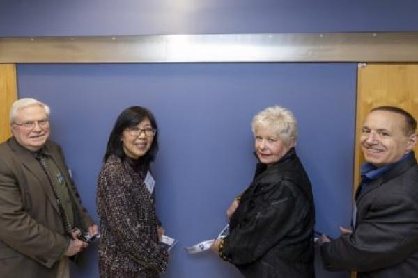 Four people cut a ribbon to present a plaque to name a research laboratory