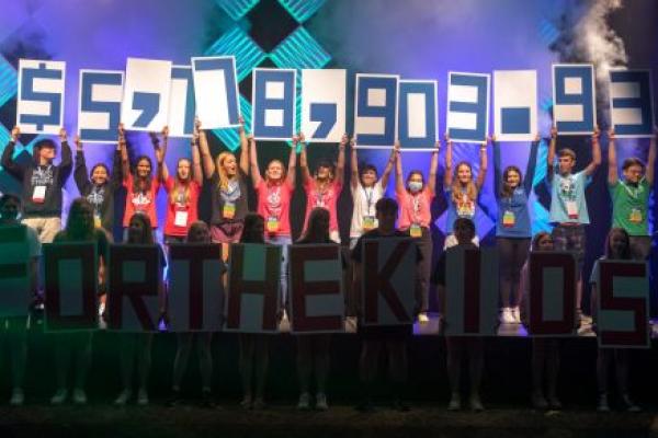 Students hold up signs with numbers on them to reveal a fundraising total of more than $5.7 million