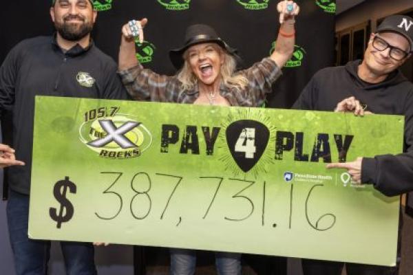 Three people smile enthusiastically as they pose with poster containing the dollar amount $387,731.16.