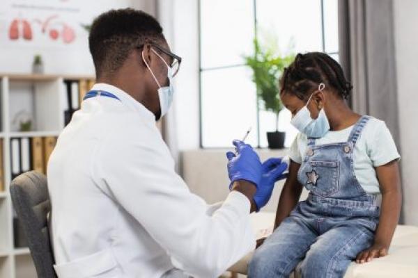 A doctor prepares to give an injection to a young girl.