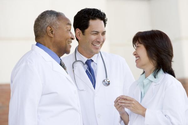 Three Doctors Standing Outside A Hospital Chatting To Each Other Laughing